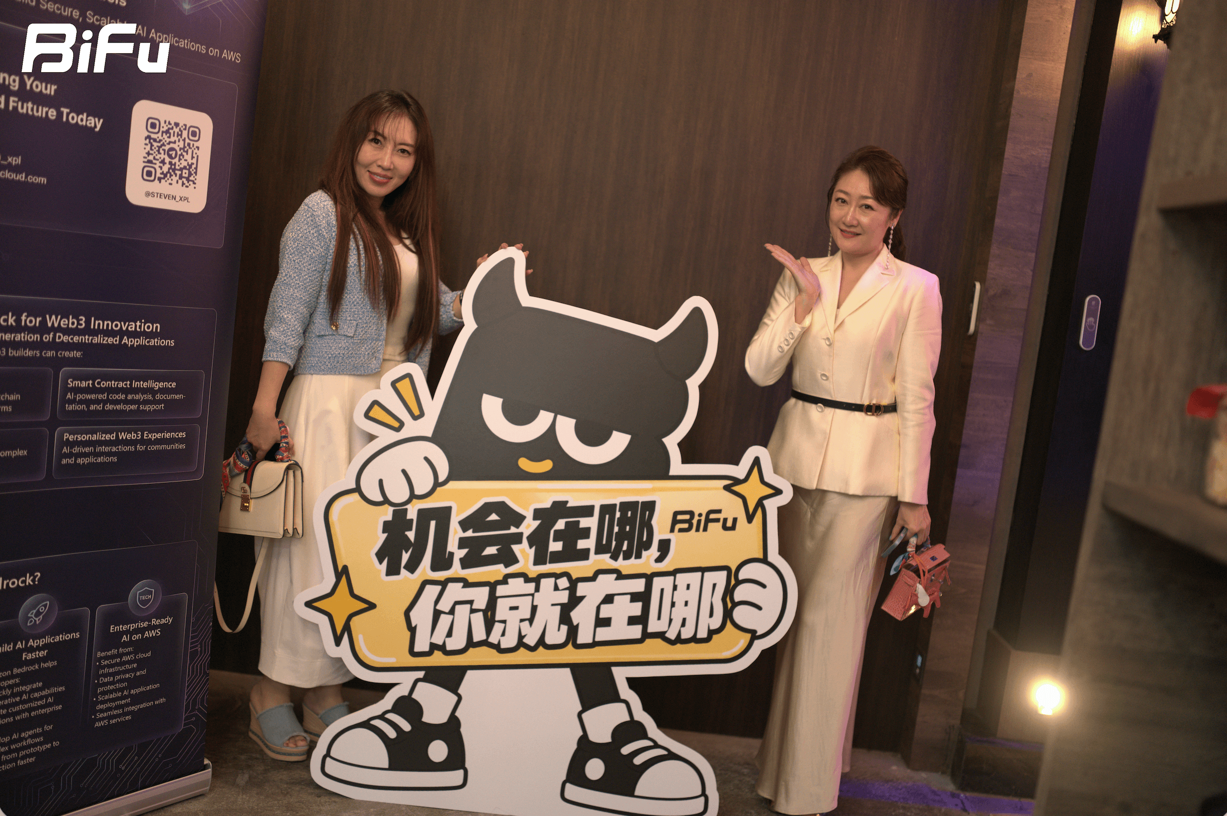 The picture shows two women standing next to a signboard with the text "机会在哪，BiFu 你就在哪" (Where is the opportunity, BiFu is there) and a cartoon character. There is a BiFu logo and a QR code on the left side of the image. This photo is related to the BiFu首秀Token2049: RWA主题晚宴与酒会 activity mentioned in the document, which is a dinner event where BiFu invites industry partners to discuss RWA-related issues.
